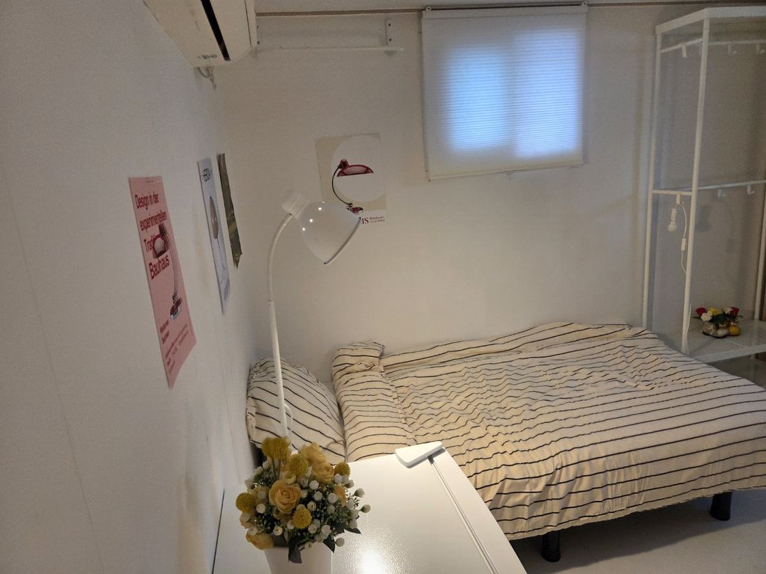 가산동 고시원 끄라샤하우스 가산점 창가에 침대와 행거 선반이 있는 객실